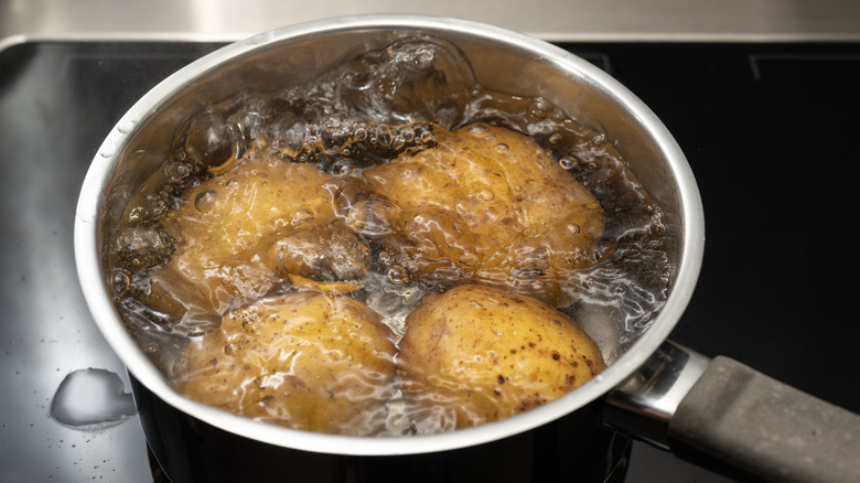 whole, unpeeled potatoes boiling in a pot