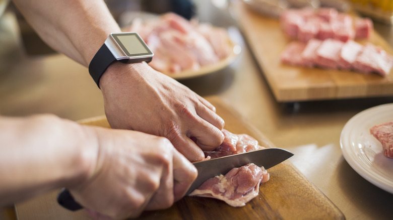 Hands cutting into chicken 