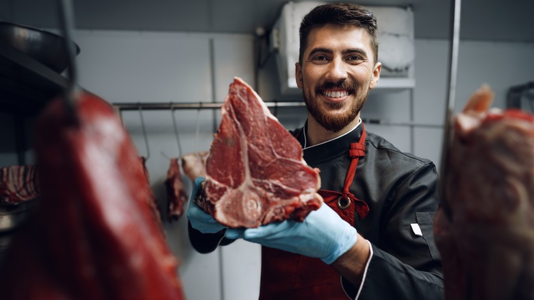 butcher holding a cut of meat with a bone