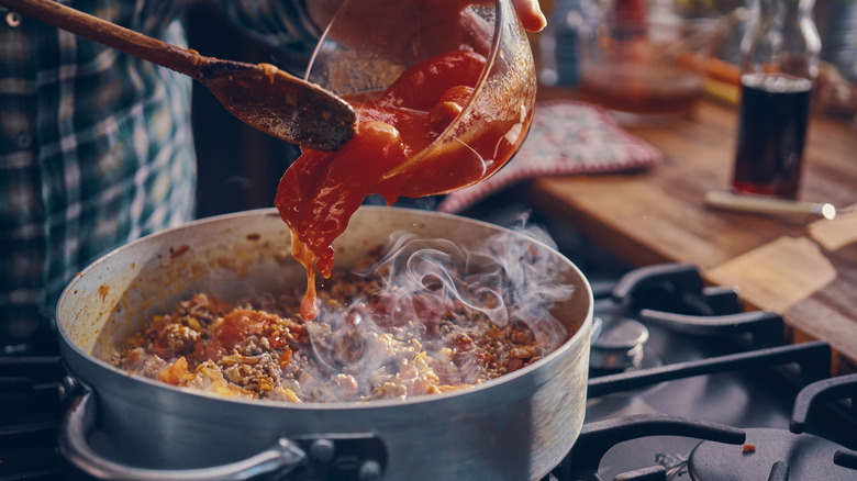 Pouring bowl of tomatoes into pot 