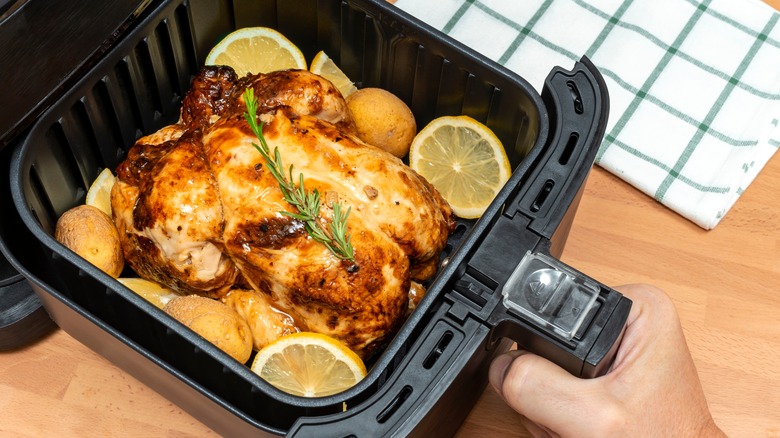 Air fryer basket with a whole roast chicken inside