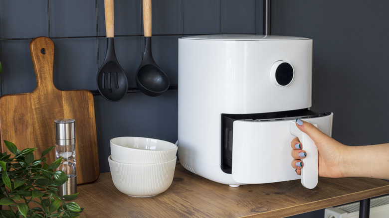 Person using an air fryer on a kitchen table