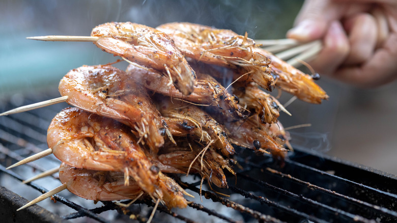 Shrimps on skewers over grill