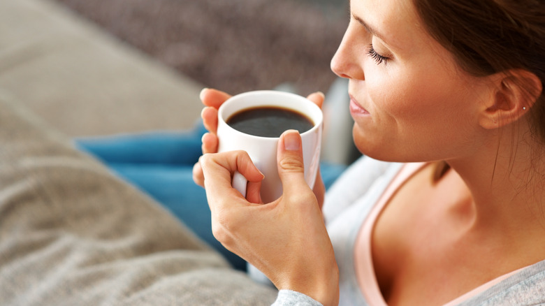 person drinks black coffee mug