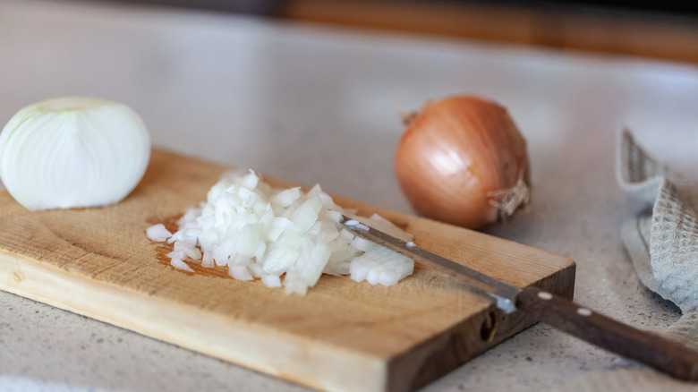 Diced onions on a cutting board with a knife