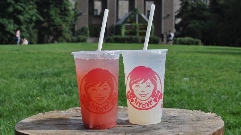 Pink and standard lemonade on wooden stump outdoors