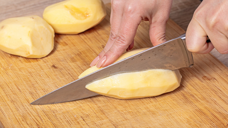 Person cutting potato with knife