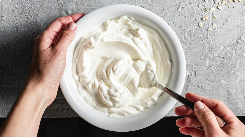 Person stirring whipped cream in a bowl