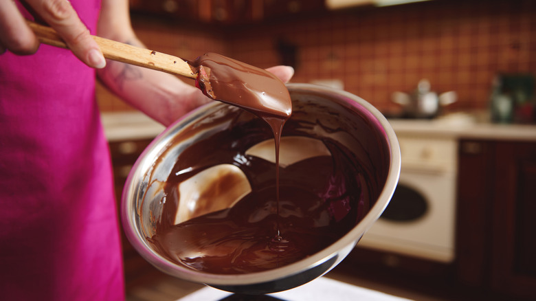 person in home kitchen making tempered chocolate in a bowl