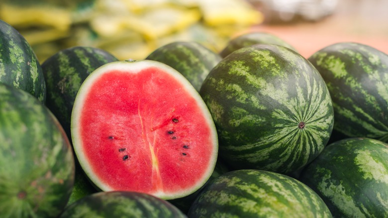 Half watermelon amidst whole watermelons