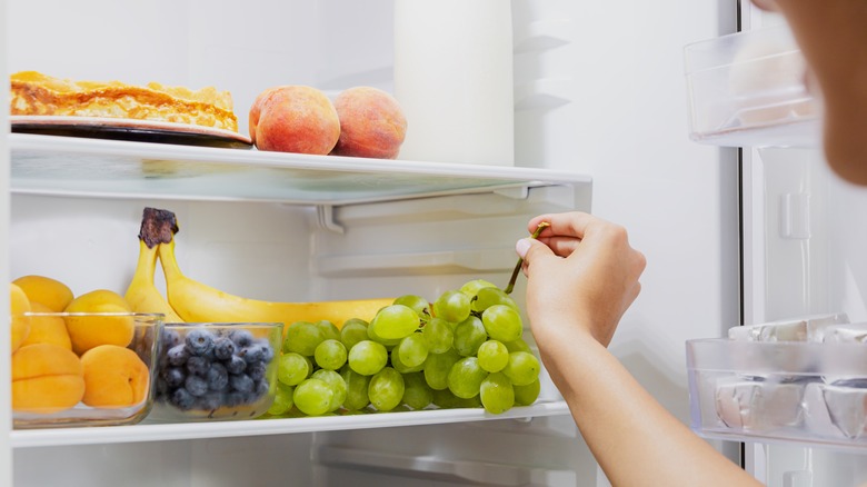 Hand putting grapes in the fridge