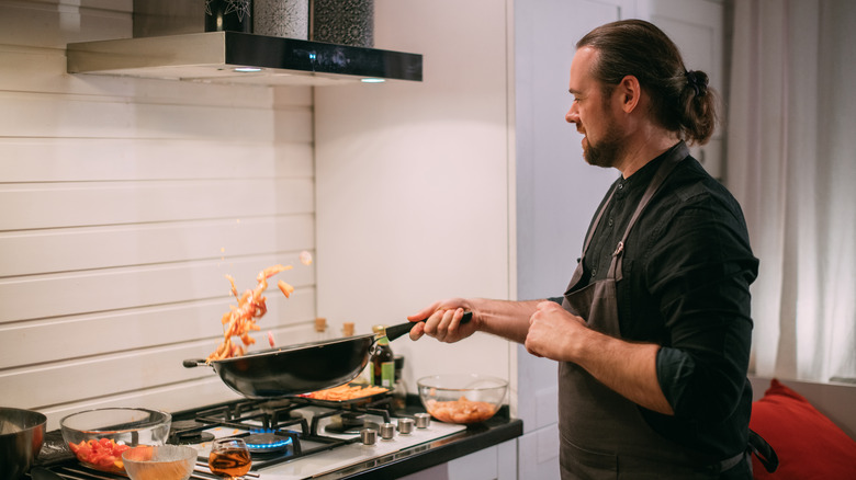 Man cooking with wok at home 