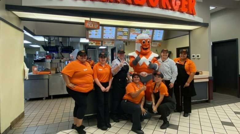 Employees posing in front of a Whataburger.