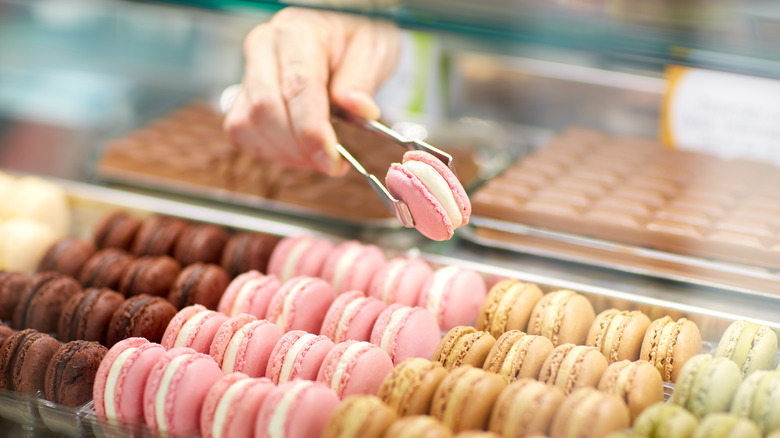 Server picking up a pink macaron