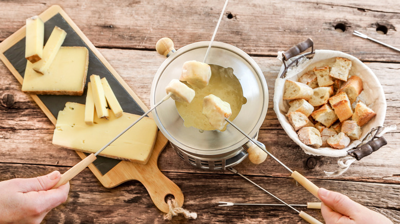 hands dipping bread into cheese fondue