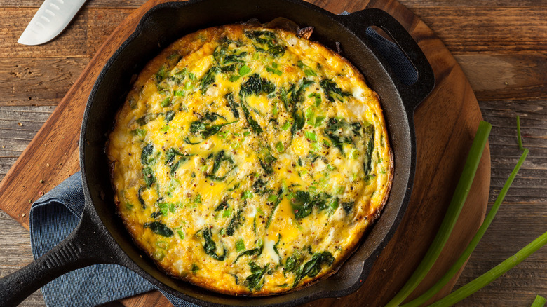 spinach frittata in pan on cutting board