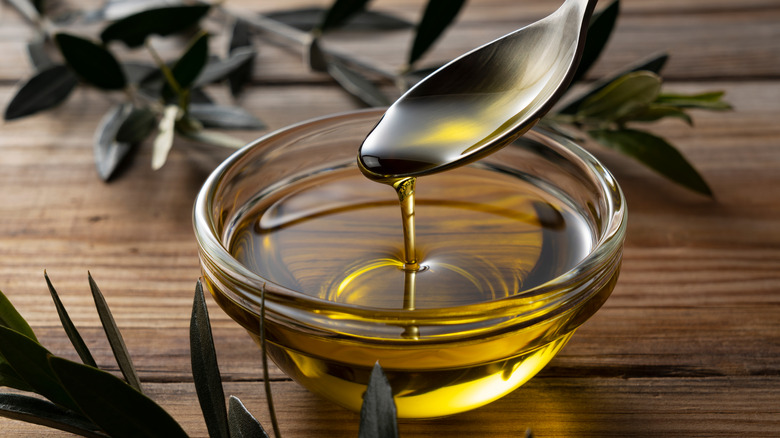 Spooning olive oil into bowl