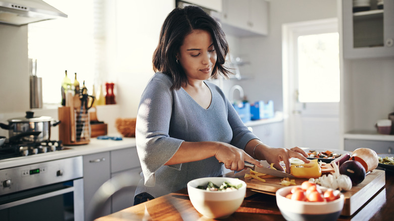 woman chopping vegetables on a cutting board