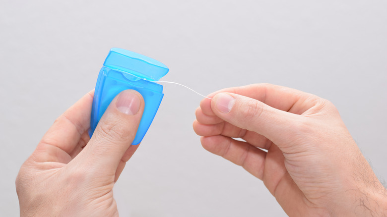 Pulling dental floss from package