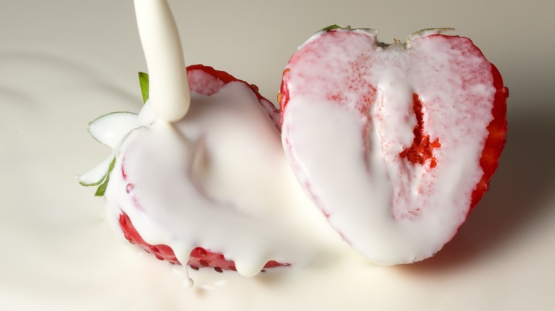 Heavy cream poured over strawberry halves