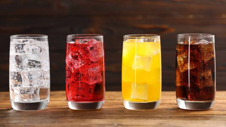 four glasses of different soda flavors