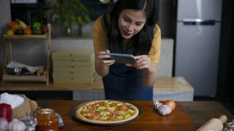 Woman taking photo of a pizza