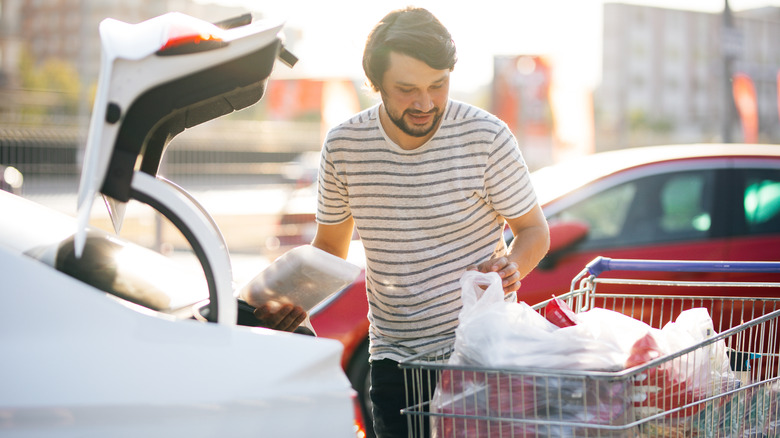 Person putting groceries in trunk