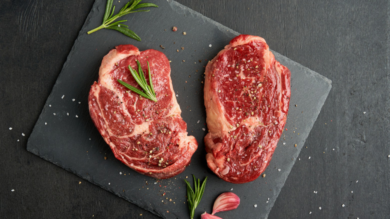 two rib eyes with salt, pepper, and herbs