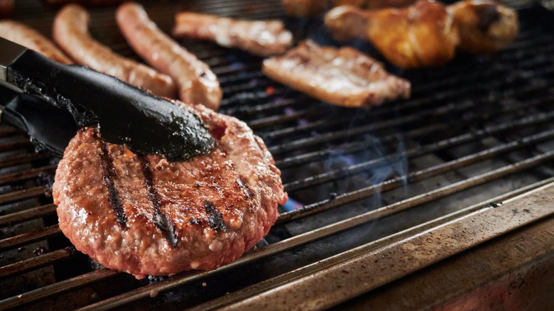 tongs flipping burger on grill