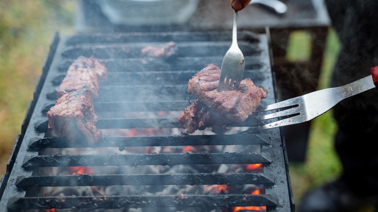 Flipping grilled meat with forks