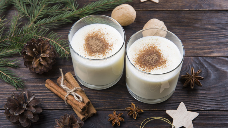 Eggnog with cinnamon in glasses with Christmas decor on a wooden table