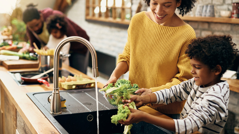 family washing lettuce in a kitchen sink