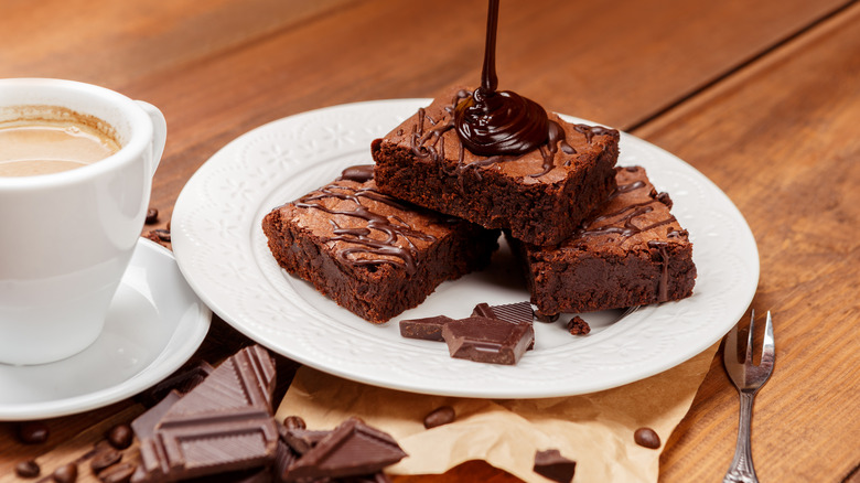 Plate of brownies with drizzle of chocolate pouring from above