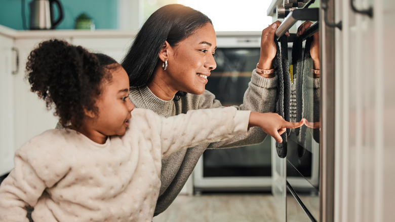 Adult and child looking into oven