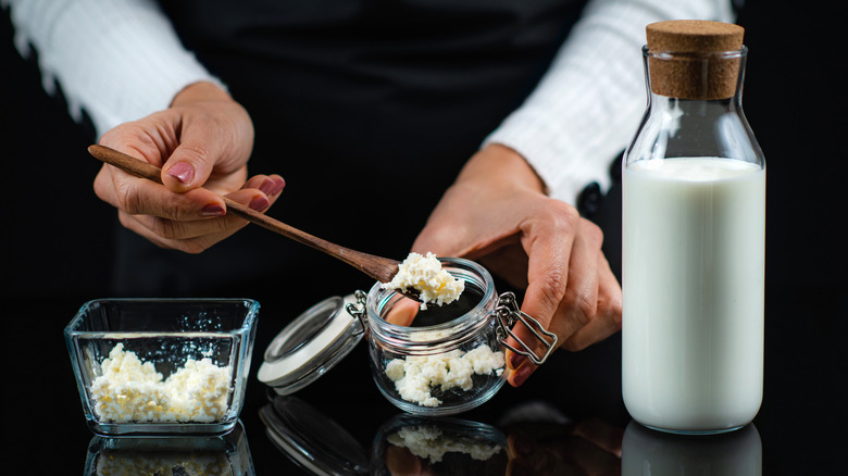 A woman scoops kefir grains out of a jar