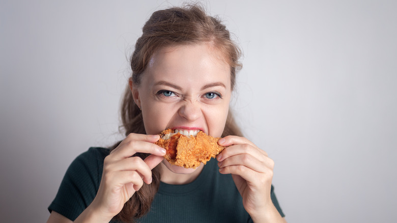 Person biting into fried chicken