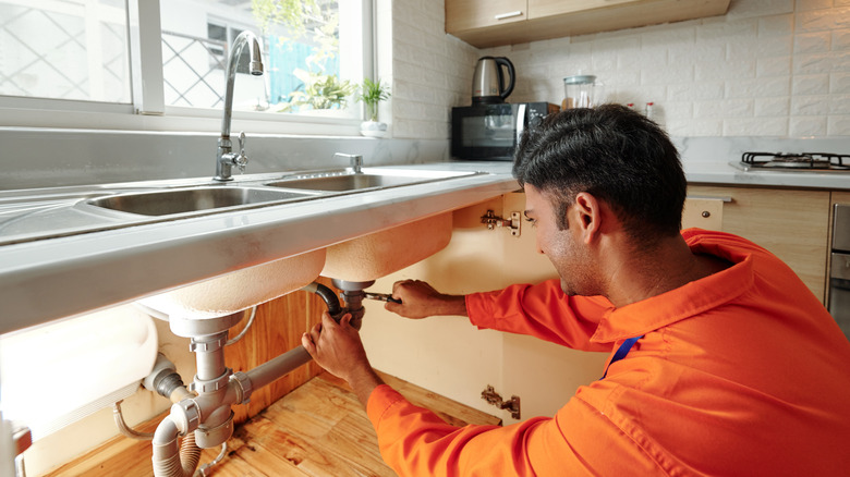 man looking under kitchen sink 