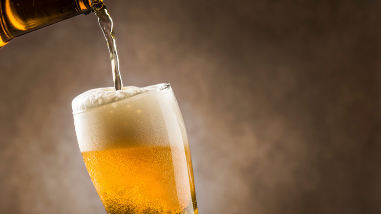 Pouring a lager beer from a brown bottle into a clear glass