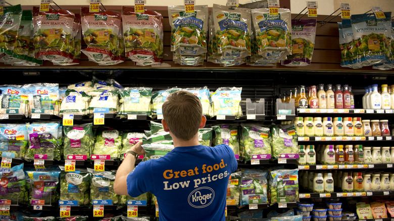 An employee stocks salad mix