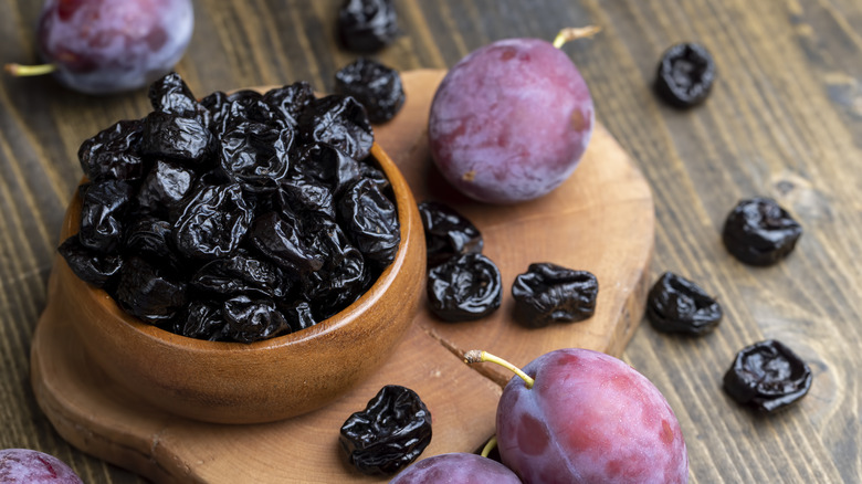 Prunes in wooden bowl with plums