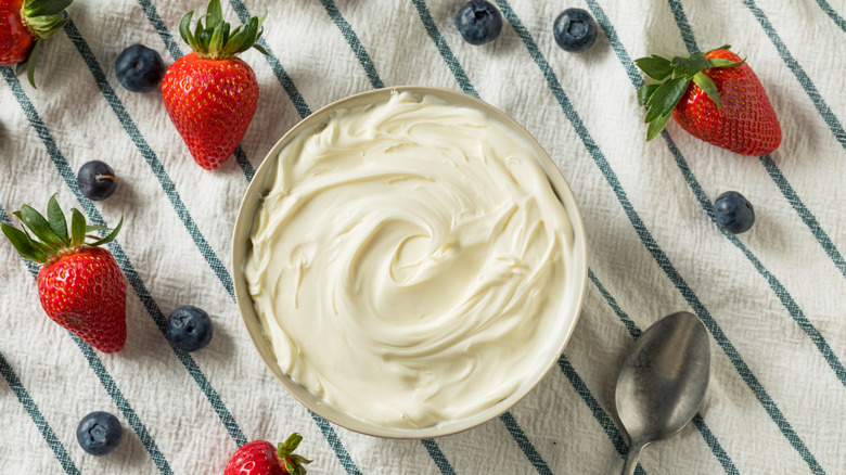 bowl of mascarpone on tablecloth next to berries 