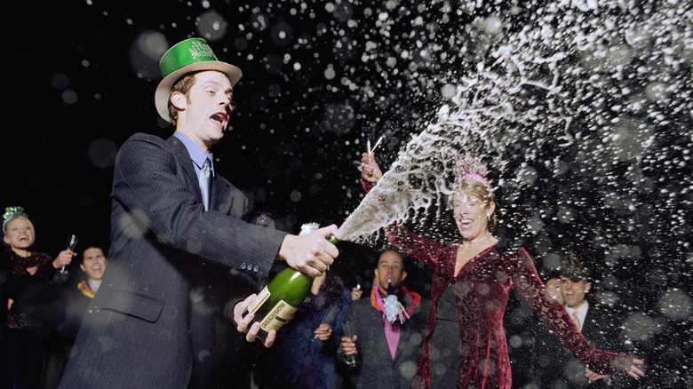 Man spraying a bottle of champagne at a party