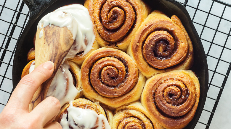 Spreading icing on cinnamon rolls