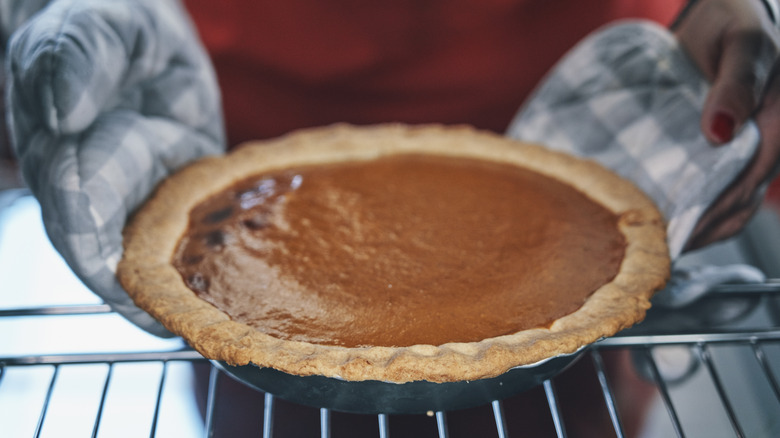 Taking a pumpkin pie out of the oven