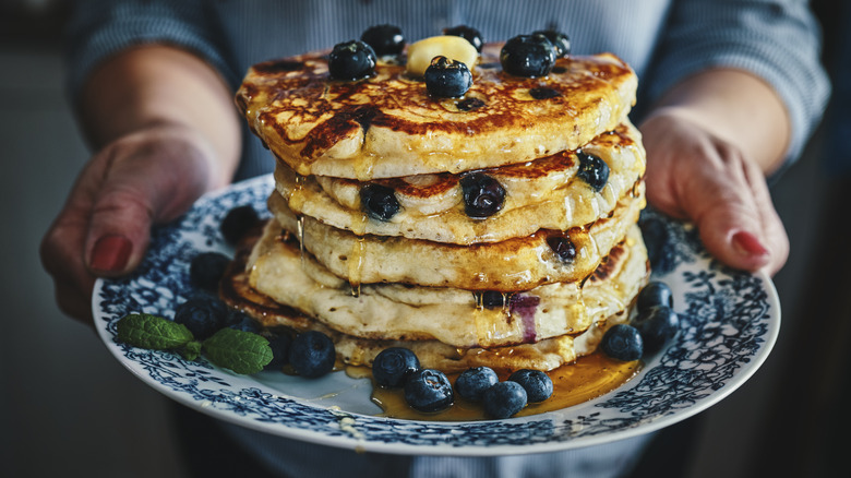 Person holding stack of pancakes