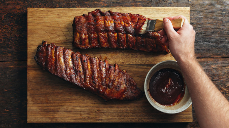 adding barbecue sauce to ribs