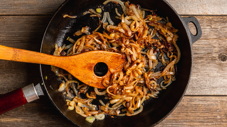 Wooden spoon stirring caramelized onions