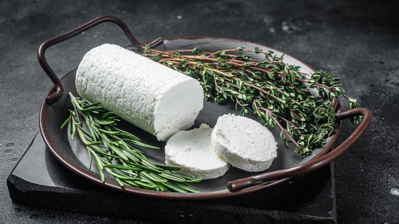 cut up log of chevre on pain with herbs