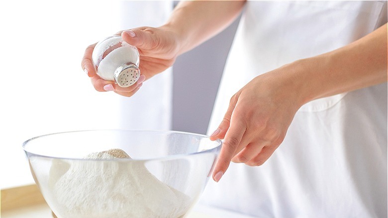 Hand shaking salt into bowl