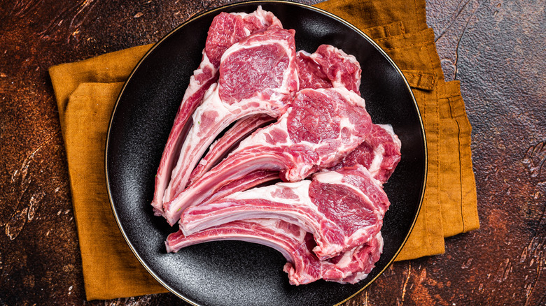 A plate stacked with many raw lamb chops